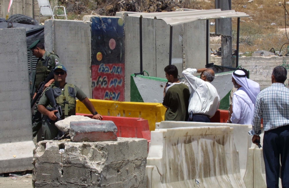 Palestinians wait at a checkpoint to enter the city from the West Bank.