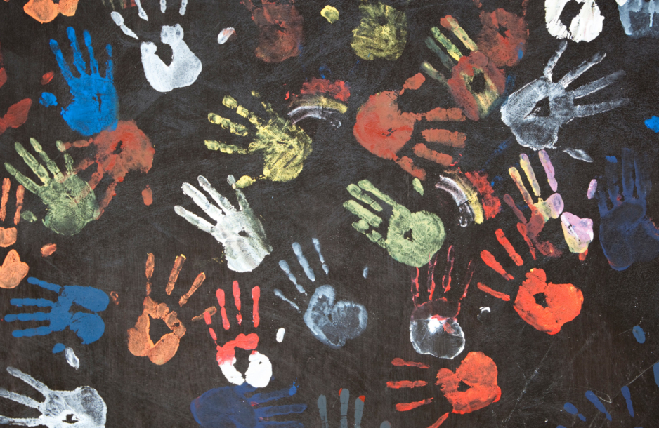 Multi-colored paint handprints on a dark wall