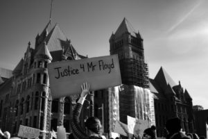 A person holds a Justice 4 Mr Floyd sign outside City Hall in downtown Minneapolis, Minnesota as the trial of former Minneapolis police officer Derek Chauvin begins. Image by Lorie Shaull.