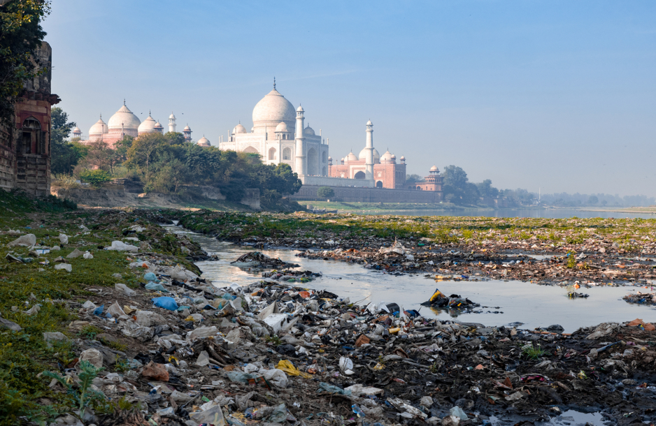 Plastic waste in a river with the Taj Mahal in the background.