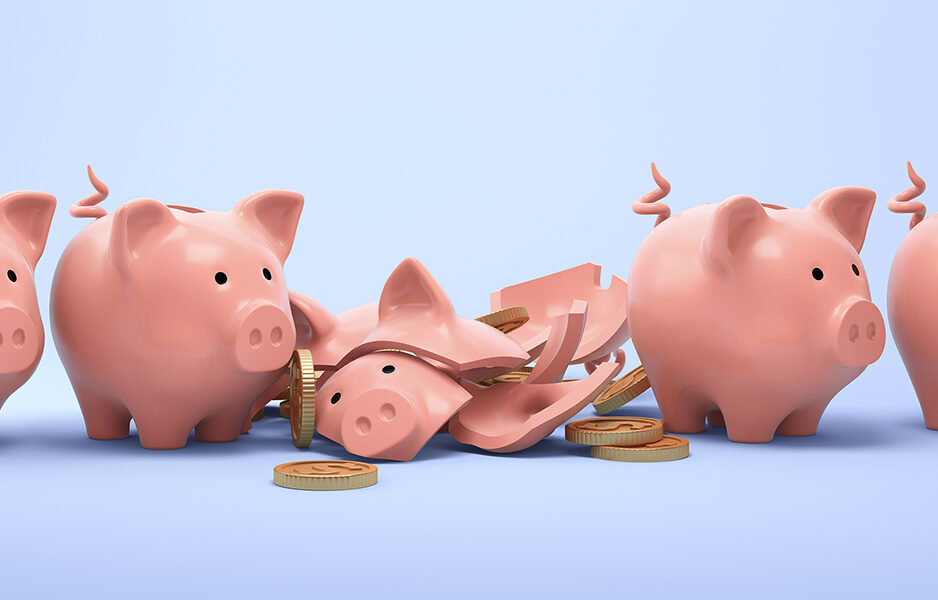 Four ceramic piggy banks with one broken into pieces on blue background